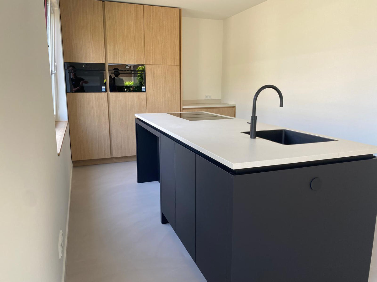 Maatwerk keuken met zwart kookeiland en lichte houten kastenwand