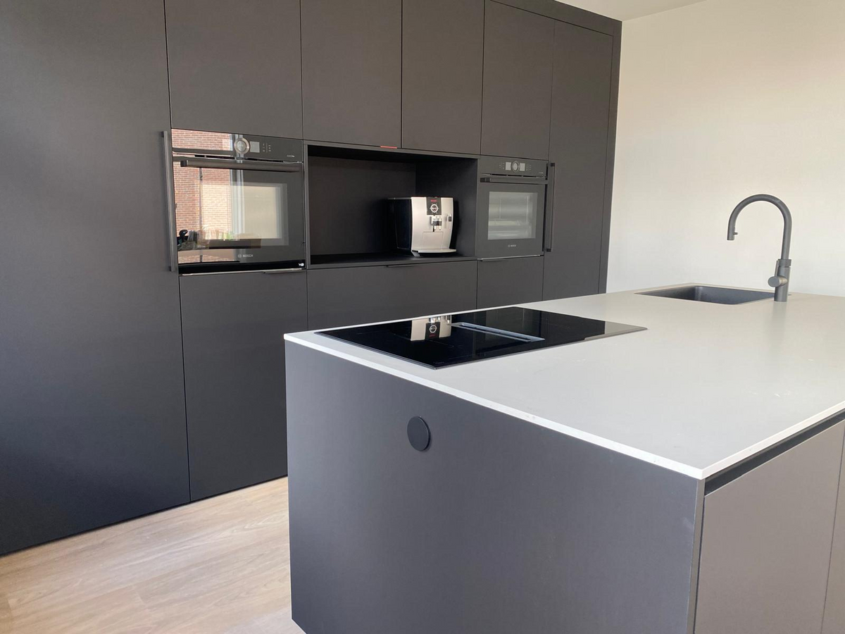 Donkere maatwerk keuken met kookeiland en lichte accenten