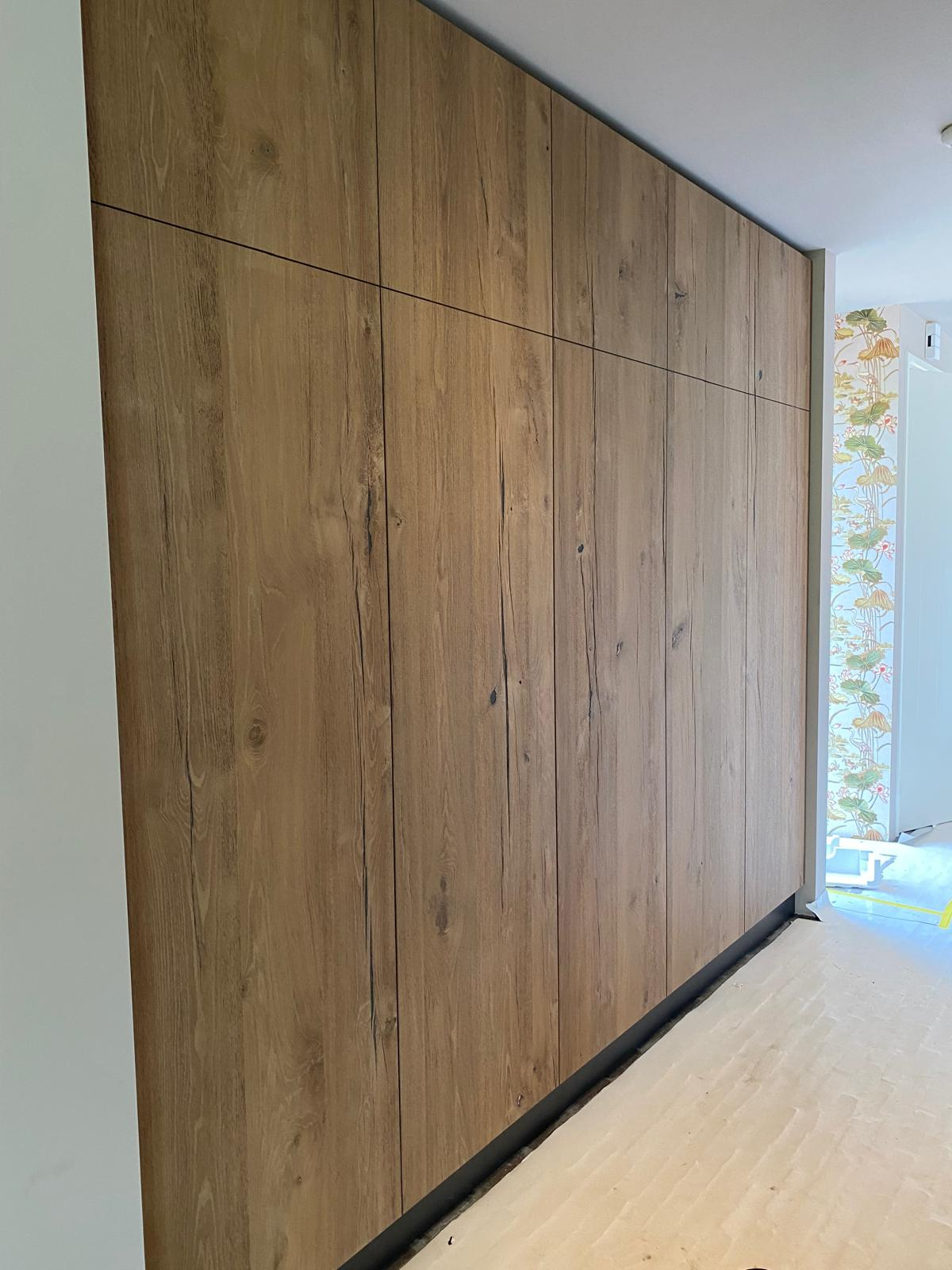 Hoge maatwerk kastenwand met natuurlijke houtstructuur