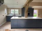 Donkergrijze maatwerk keuken met kookeiland en houten balkconstructie