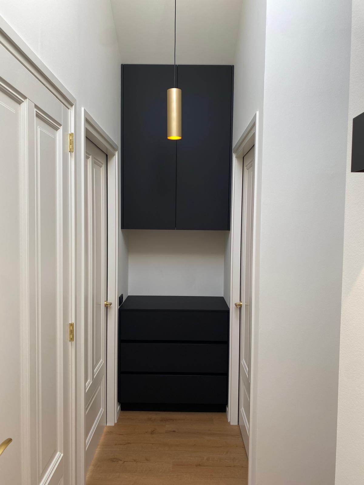 Zwart maatwerk meubel in de hal met messing verlichting