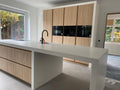 Lichte houten maatwerk keuken met kookeiland en geïntegreerde bar