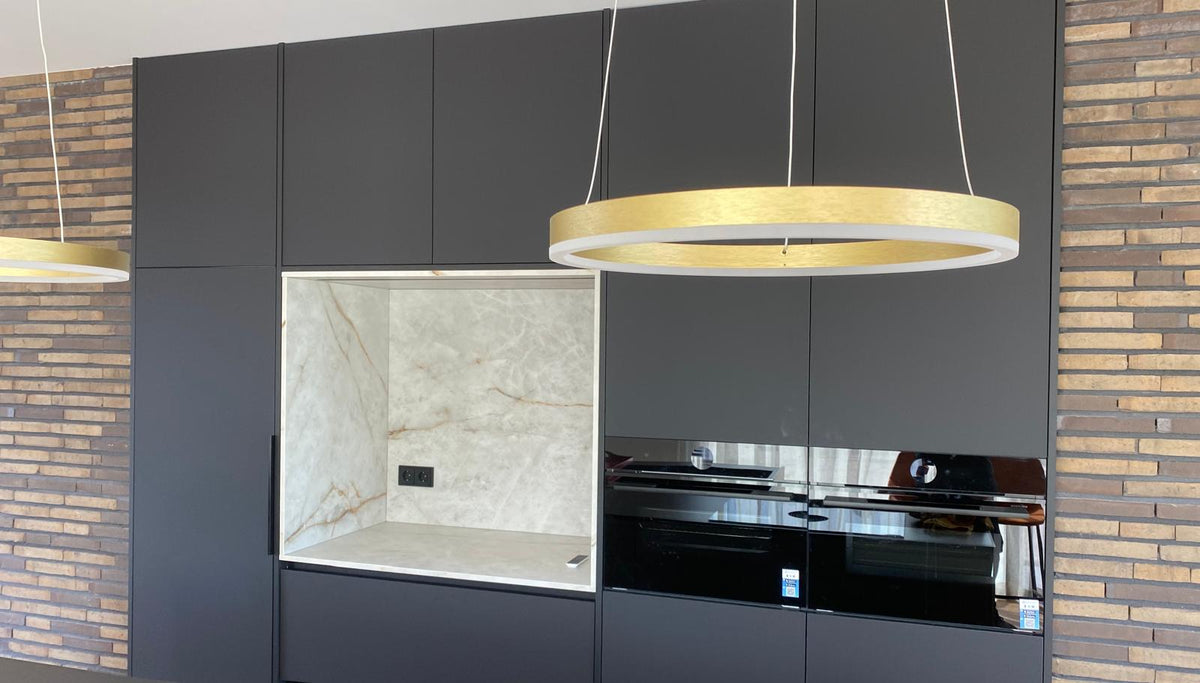 Luxe maatwerk keuken met goudkleurig kookeiland en donkere kastenwand