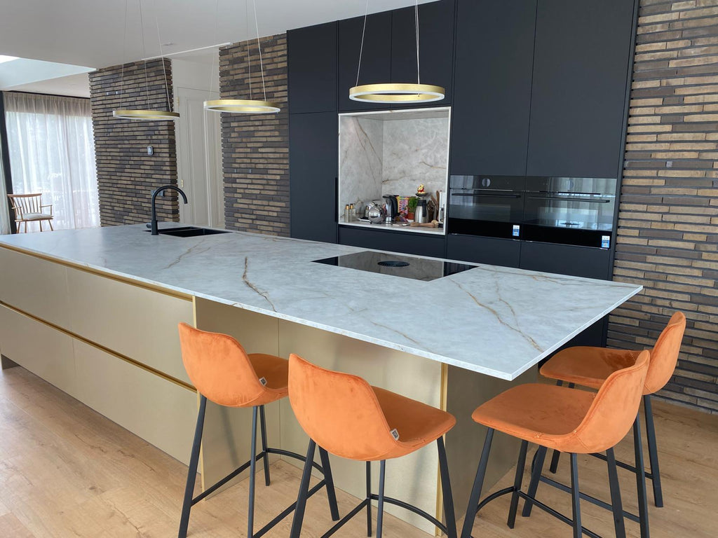Luxe maatwerk keuken met goudkleurig kookeiland en donkere kastenwand