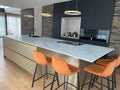 Luxe maatwerk keuken met goudkleurig kookeiland en donkere kastenwand