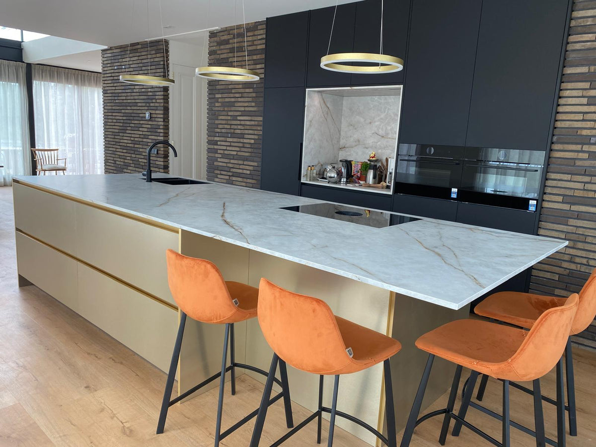 Luxe maatwerk keuken met goudkleurig kookeiland en donkere kastenwand