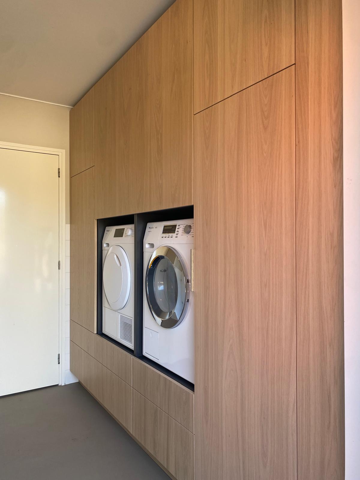 Maatwerk wasruimte met houten kastenwand