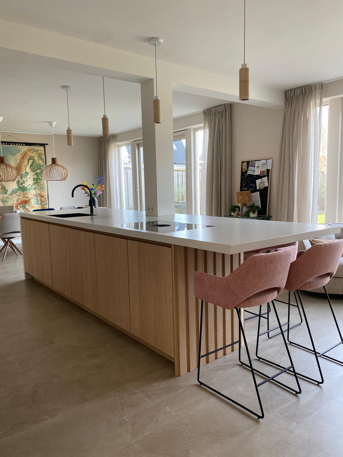 Lichte maatwerk leefkeuken met houten kookeiland en zitgedeelte