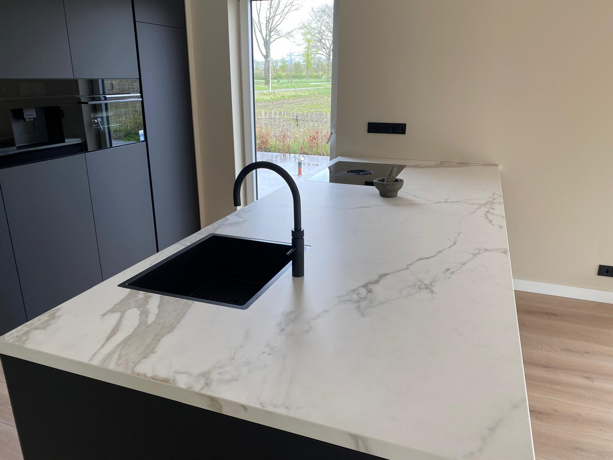 Donkere maatwerk keuken met kookeiland en licht werkblad.