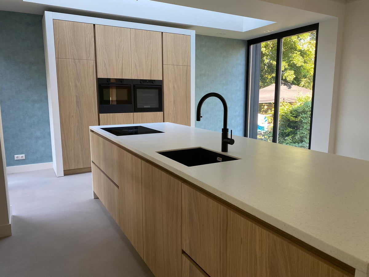 Maatwerk keuken met houten kookeiland, licht werkblad en hoge kastenwand